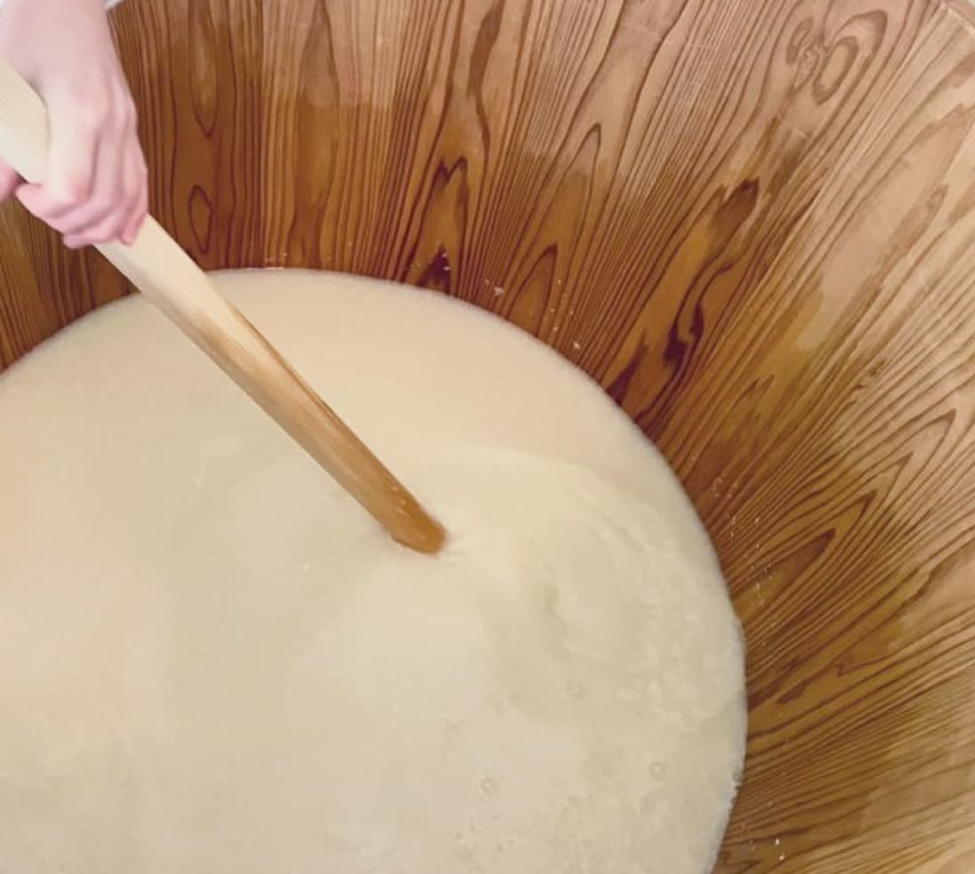 大きなボウルの液体をかき混ぜている人物の画像